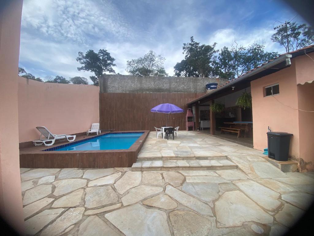 a patio with a pool and a table and an umbrella at Suítes Goiabal in Pirenópolis