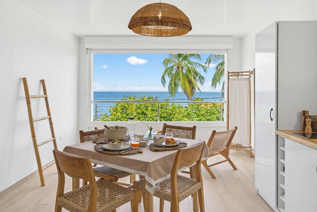 a dining room with a table with a view of the ocean at Appart'hôtel DLOKOKO Sainte Luce centre in Sainte-Luce