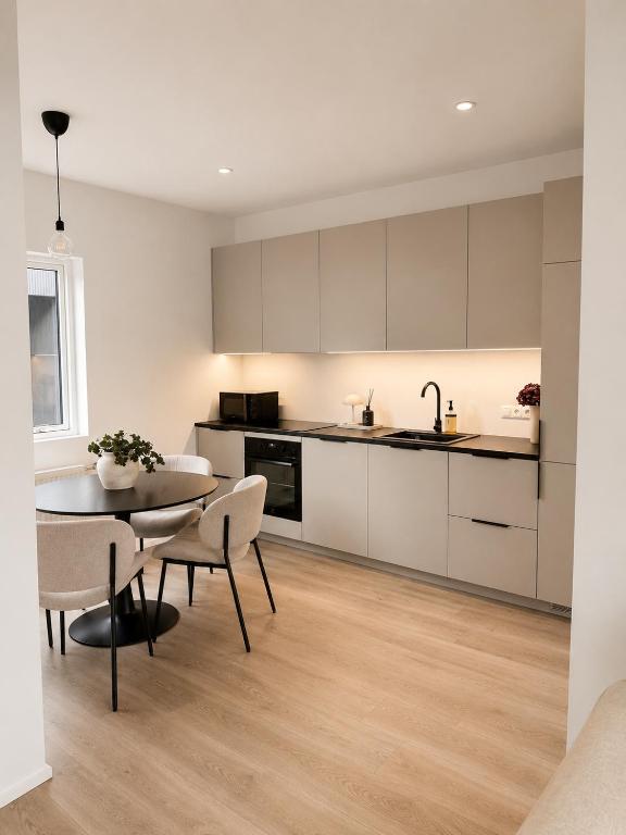 a kitchen with white cabinets and a table and chairs at New Modern Two bedroom Apartment in Hveragerði
