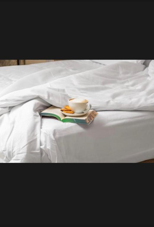 a coffee cup and a book on a bed at St Helens in Bolton