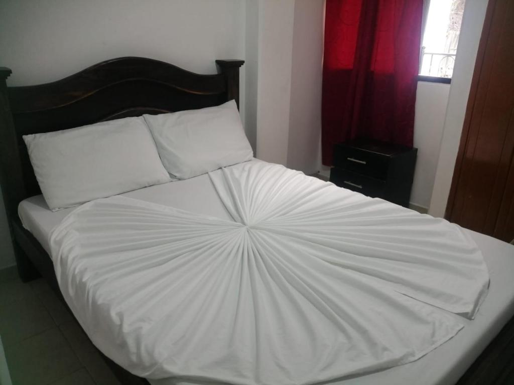 a large bed with white sheets and pillows at Hotel Cooptmotilon in Pamplona