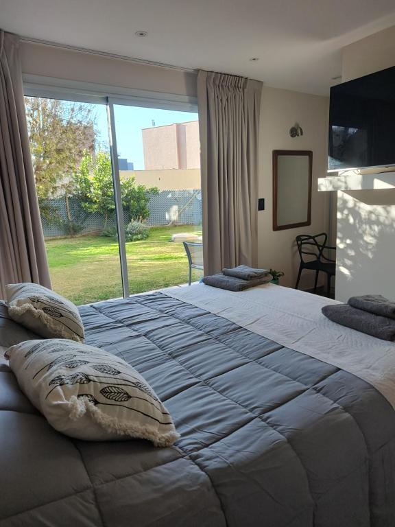 a bedroom with a large bed with a large window at Casa chacras in Chacras de Coria
