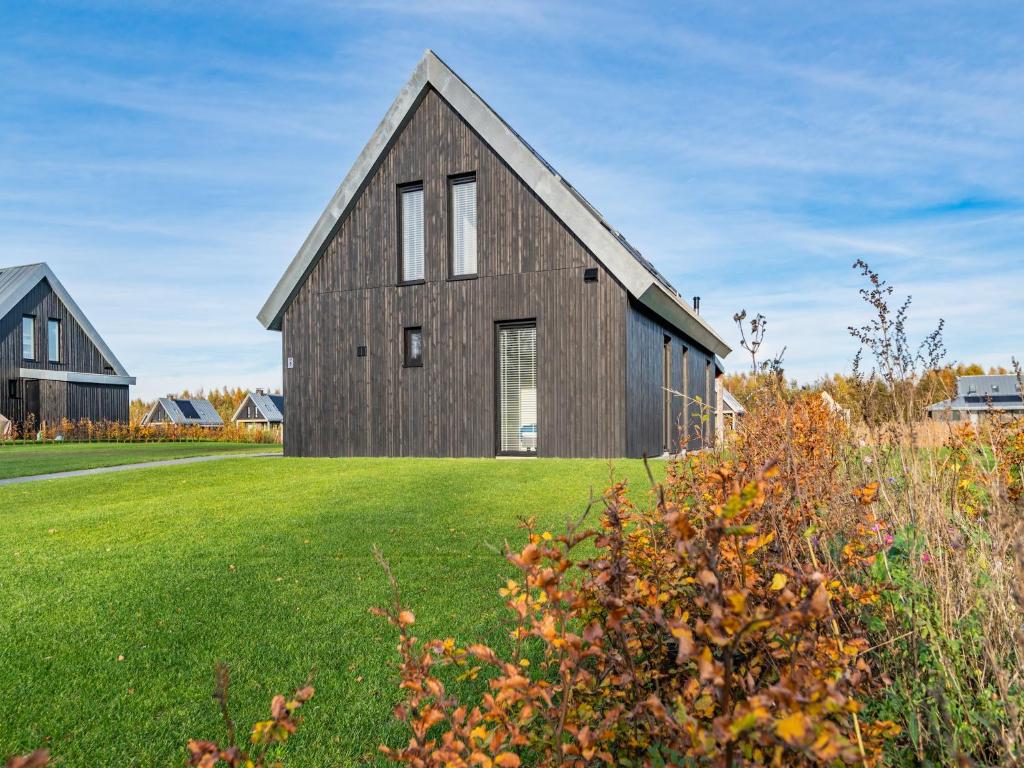 a wooden house on a grassy field at Fantastic villa located by a lake in Sint Nicolaasga