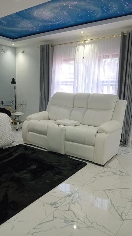 a white couch in a living room with a marble floor at Niasha Gardens in Chinhoyi