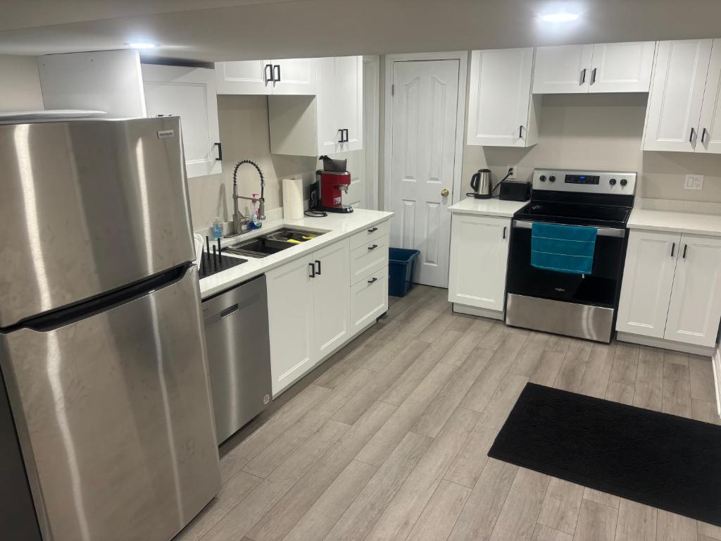 a kitchen with white cabinets and a stainless steel refrigerator at Newly Renovated 2BR Walkout Suite in the Heart of Kanata Ottawa in Ottawa
