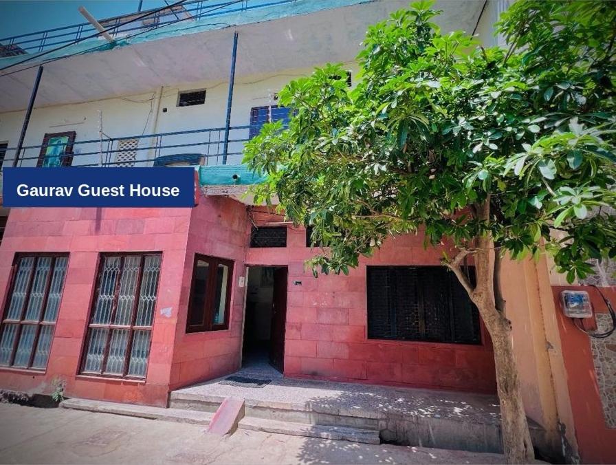 a red brick house with a tree in front of it at Gaurav Guest House in Mathura