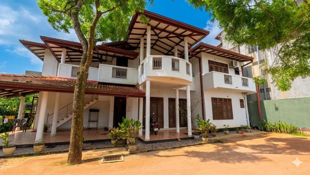a white house with a gambrel roof at Iris Grand Hotel in Nittambuwa