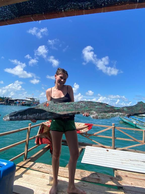 a woman standing on a pier holding a fish at Cactos Floating House Experience on Island in Lai Sơn