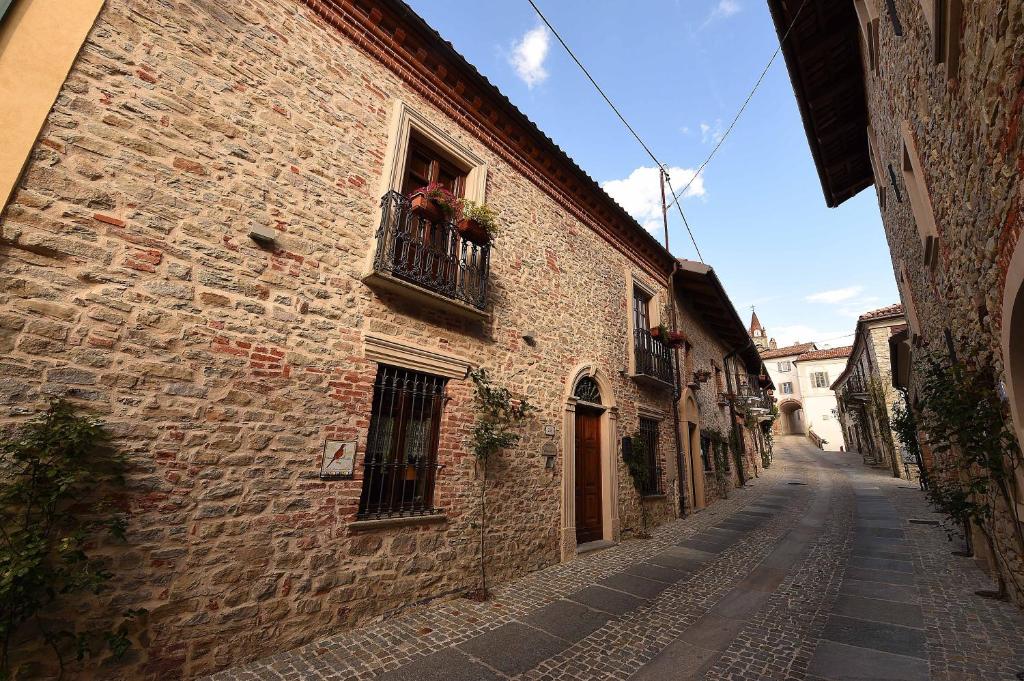 an alley in an old stone building with a balcony at Maison Christine - Family Farm in Bossolasco