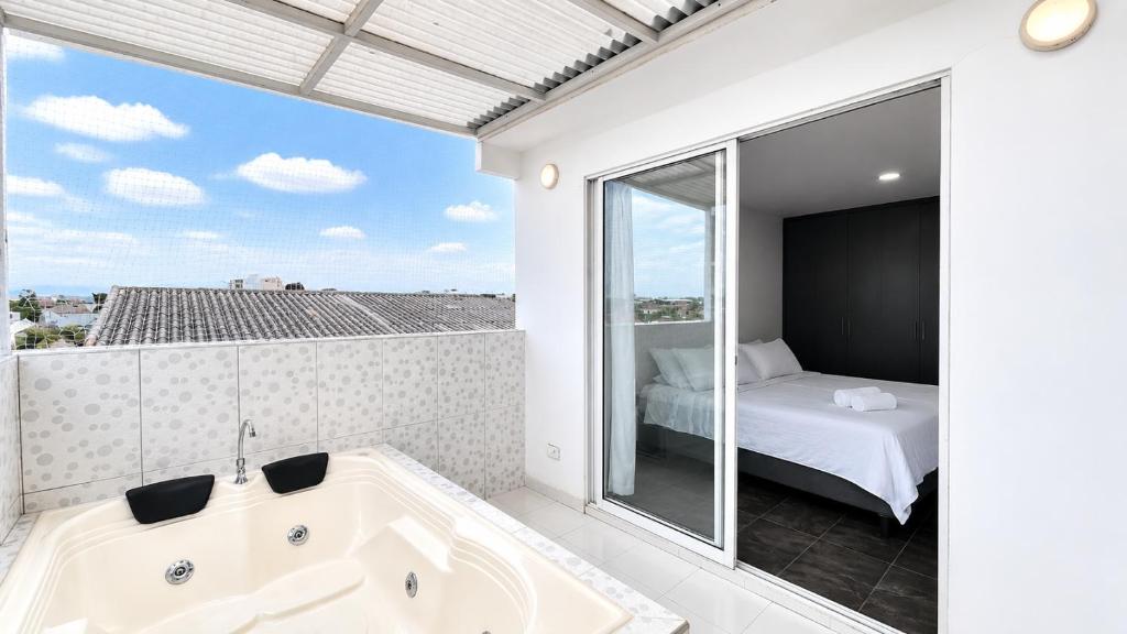 a bathroom with a tub and a bed and a window at Apartamentos cerca al centro de Cali in Cali