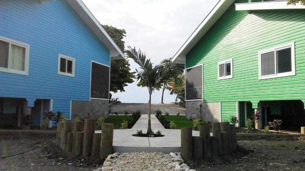 a blue and green house with a fence next to it at Serenity Beach Cottages in Utila