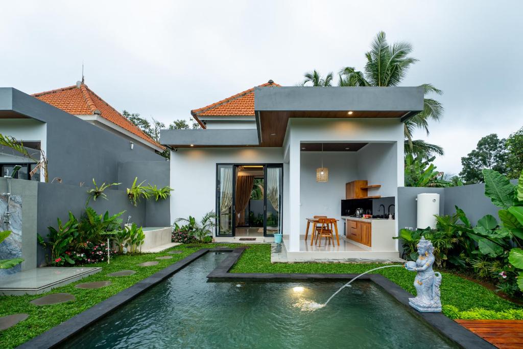 a villa with a swimming pool in front of a house at Alam Kasih Villa in Tampaksiring