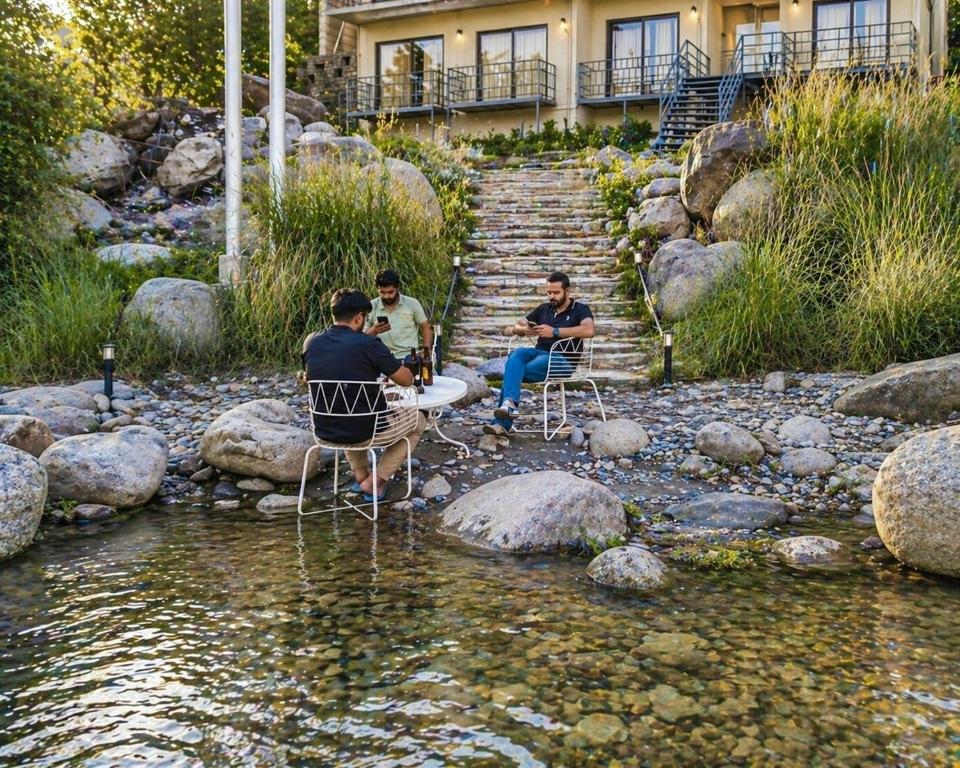 a group of people sitting around a table in a river at Aachman Riviera Valley dharamshala by NAINA STAYCATION in Dharmsāla