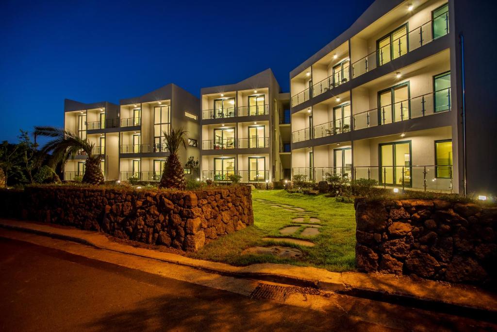 an apartment building at night with a stone wall at Poema Stay Pension in Jeju