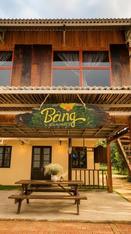 a picnic table in front of a building with a sign at BângGlamping in Hue