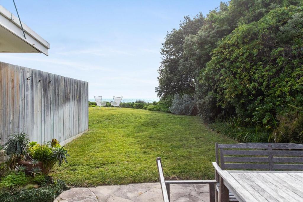 a yard with a wooden table and a bench at No 5 Red Right on the beach! in Robe