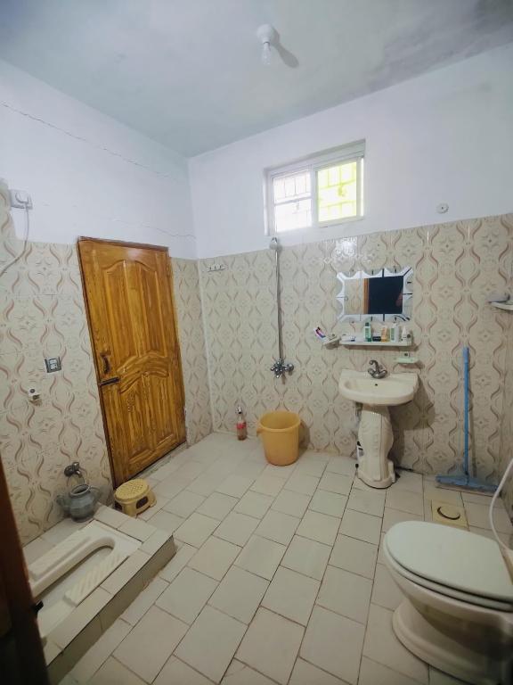 a bathroom with a toilet and a sink and a door at AR Apartment in Khaira Gali