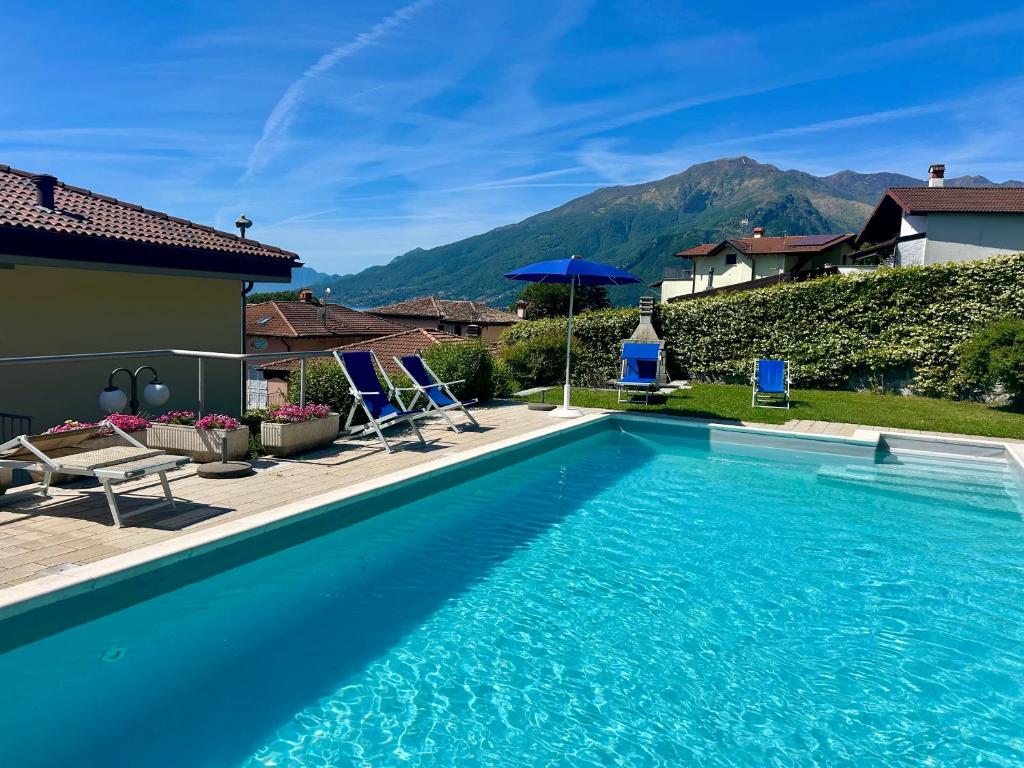 a swimming pool in front of a house with a mountain at Residence Il Bosso in Domaso