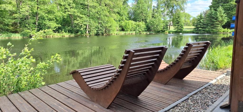 two chairs sitting on a deck next to a river at Apartamenty Młyn in Męcikał