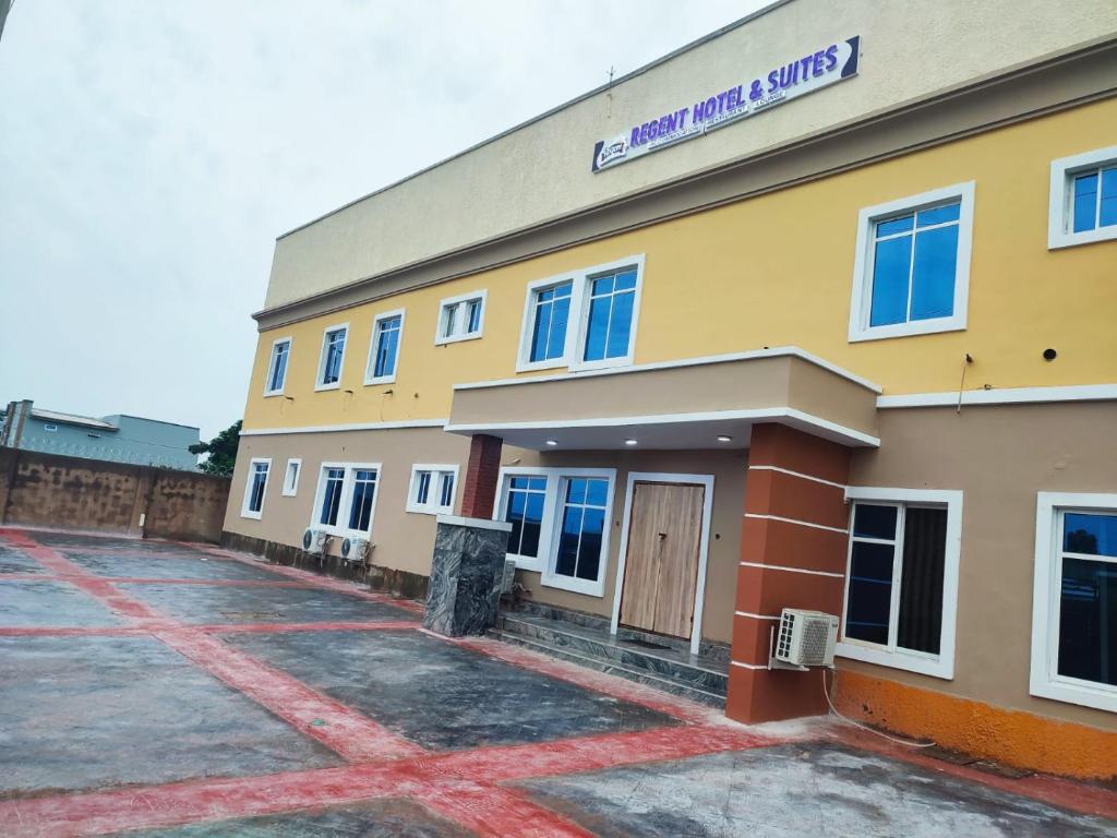 a large yellow building with blue windows on it at Regent Hotels and Suites in Oshogbo