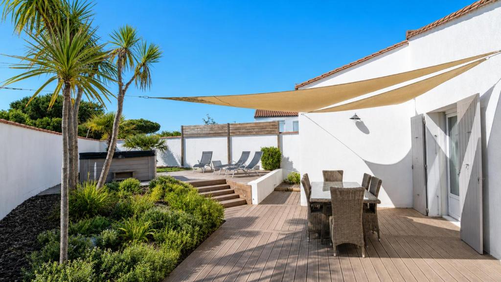 a patio with a table and chairs and palm trees at Villa Odys in Rivedoux-Plage