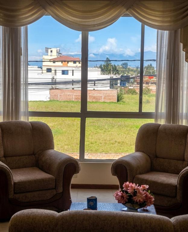 a living room with two chairs and a large window at La Casa del Turista Riobamba in Riobamba