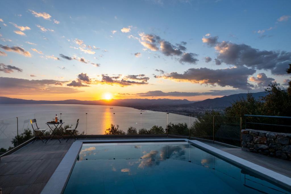 a swimming pool with a sunset in the background at Kalma Luxury Villas in Kalamata
