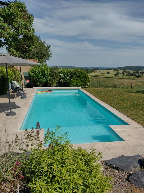 a blue swimming pool in a yard with a patio at Gîtes de beaux rêves, Glycine in Uxeau