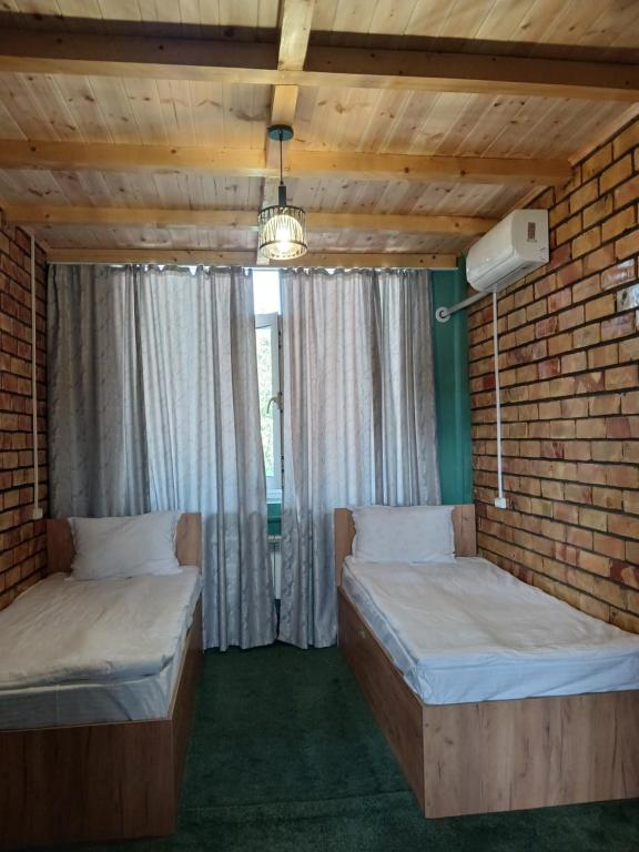 two beds in a room with a brick wall at Мурас хостел in Var-Kyshtak