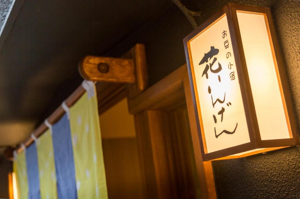 Una luz en una pared con una señal. en Hanaingen, en Kusatsu