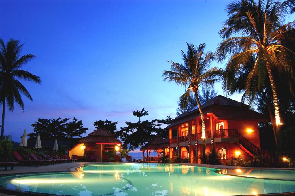 a swimming pool in front of a building with palm trees at Havana Beach Resort Phangan in Thong Nai Pan Yai