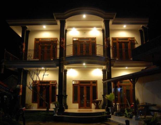 a large white building with a balcony at night at Aditya Homestay in Munduk