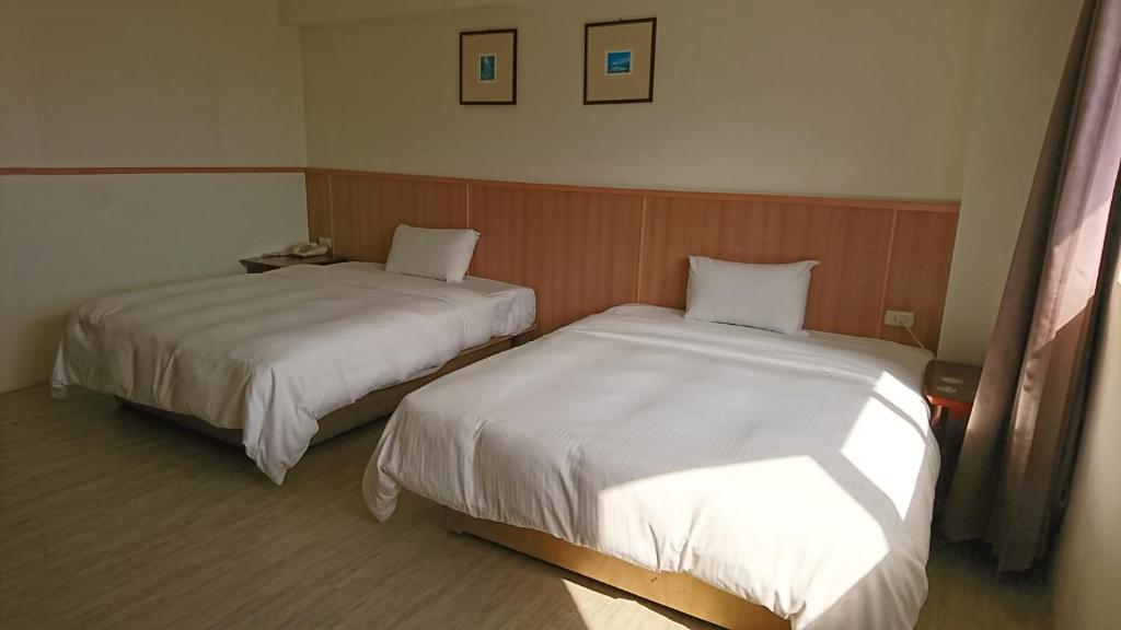 台東市的住宿－金樽大飯店，配有两张床垫的酒店客房内的两张床