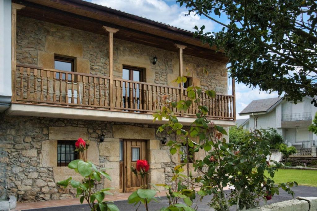 a stone house with a balcony and red flowers at Alojamientos ADRIMAR in Arnuero