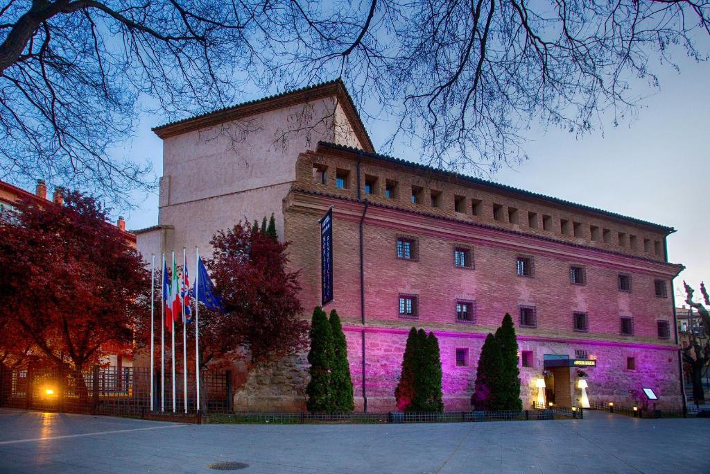 un gran edificio con luces púrpuras delante de él en Hotel Monasterio Benedictino, en Calatayud