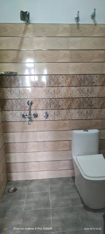 a bathroom with a toilet and a wooden wall at Rawat Homestay in Rishīkesh