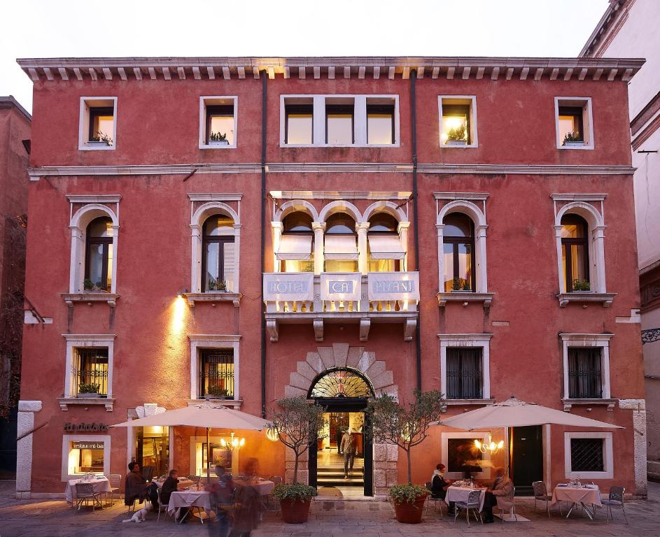 a large red building with people sitting outside of it at Ca' Pisani Hotel in Venice