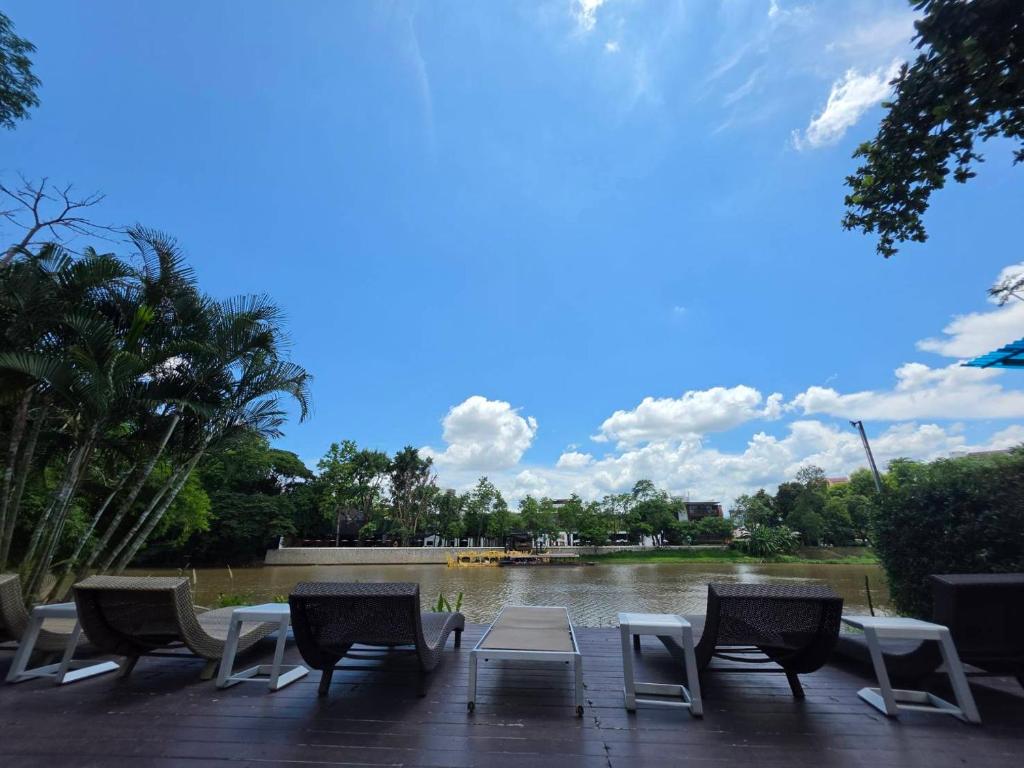 a group of chairs and tables in front of a lake at i-river chiangmai in Chiang Mai