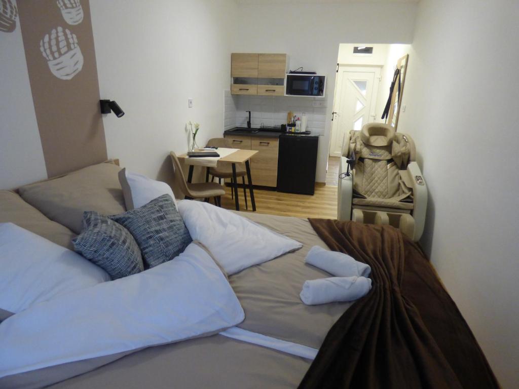 a bedroom with a bed with pillows and a kitchen at Pogácsás Apartman III in Tokaj