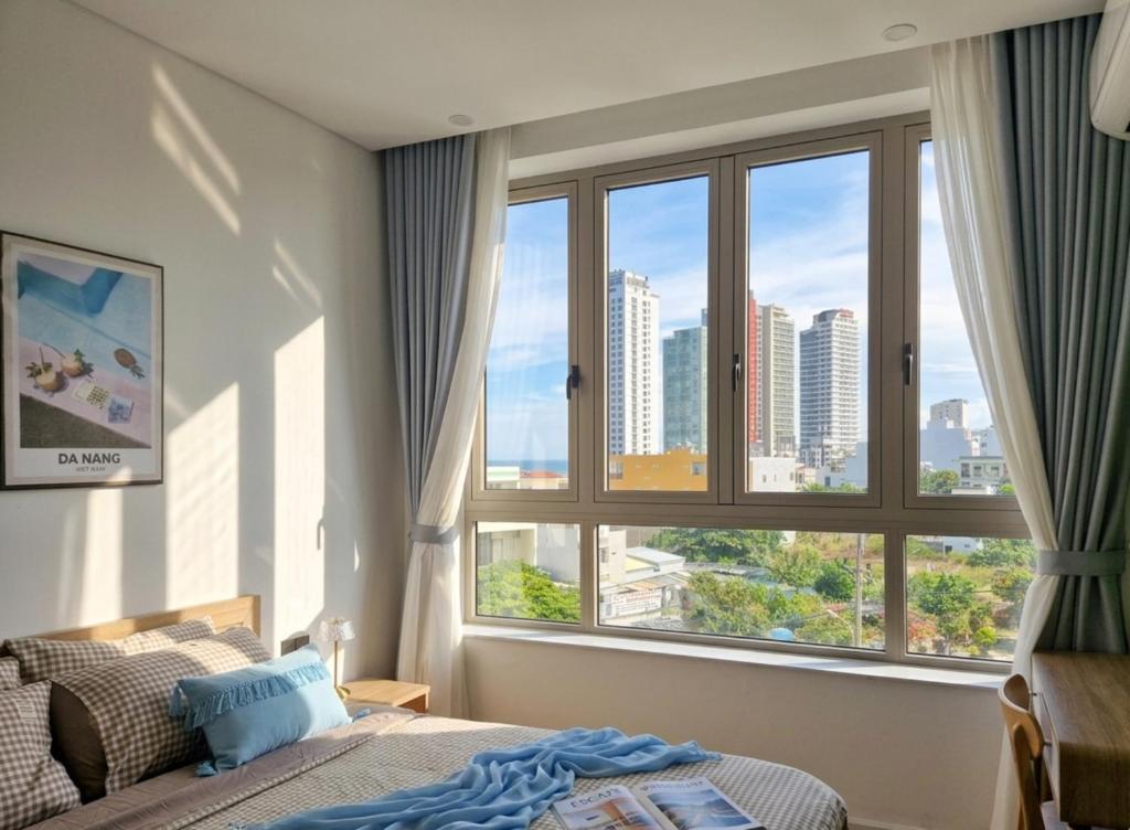 a bedroom with a bed and a large window at Seaflow Staycation in Danang