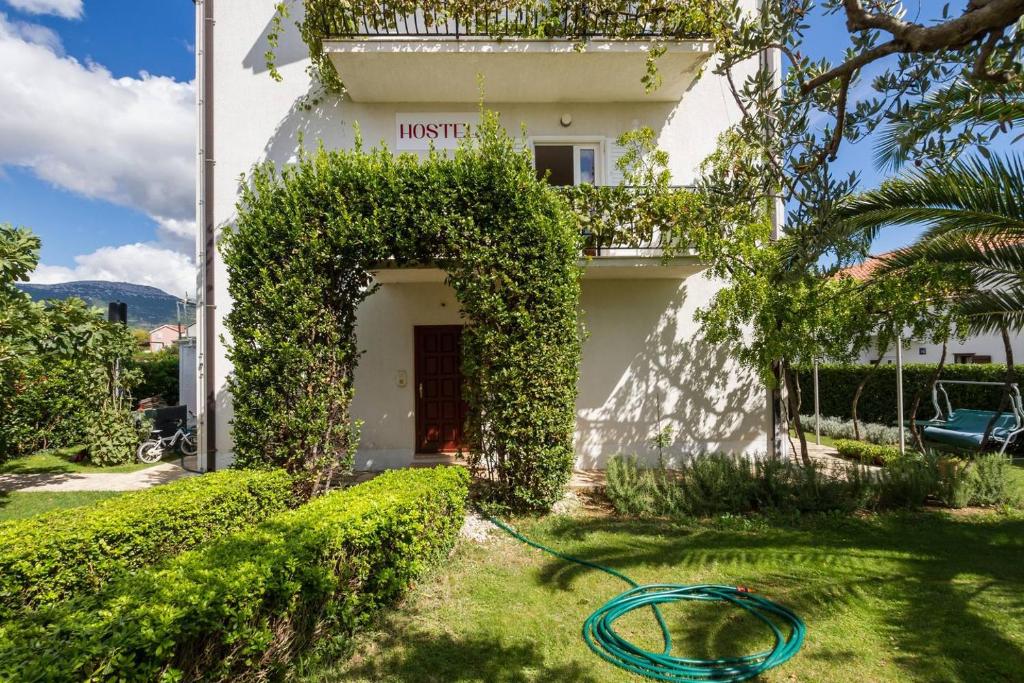 a house with a green hose in the yard at Hostel Oktarin in Kaštela