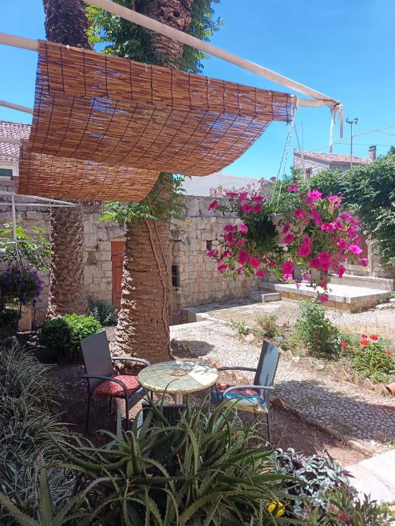 a patio with a table and chairs and flowers at Apartman Burte, Komiža in Komiža