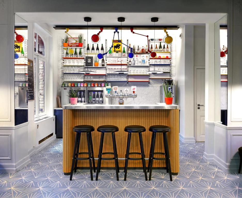 a kitchen with a bar with three stools at Vintage Hotel Brussels in Brussels