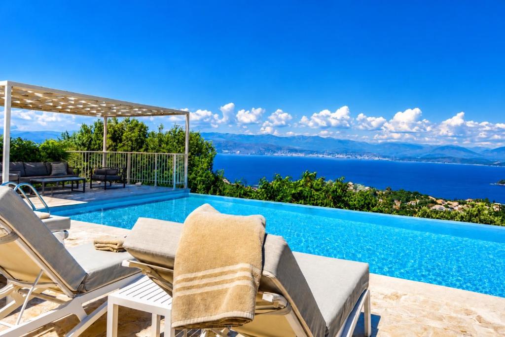 a villa with a swimming pool with a view of the ocean at Villa Helios Corfu Kassiopi in Kassiopi