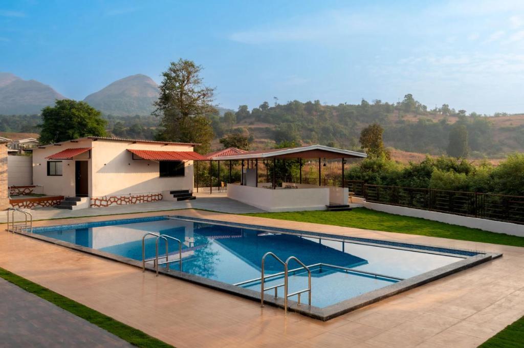 a swimming pool in front of a house at Mango Serene by Roamigo in Karjat