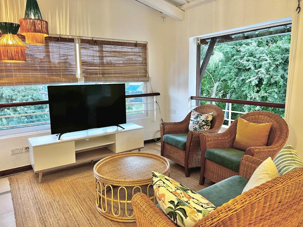 a living room with a flat screen tv and wicker chairs at Little Palm Penthouse in Cap Malheureux