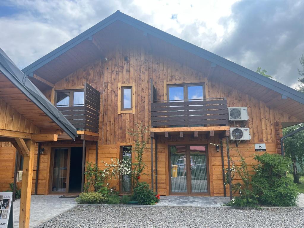 a large wooden house with a balcony on it at Noclegi Zakątek in Okuninka