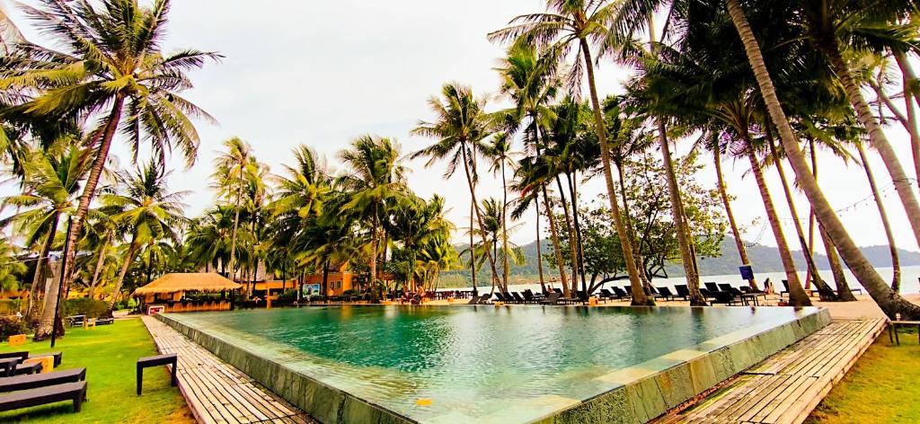 a swimming pool with palm trees in a resort at Luxury Beachfront SeaView Apartment in Ko Chang