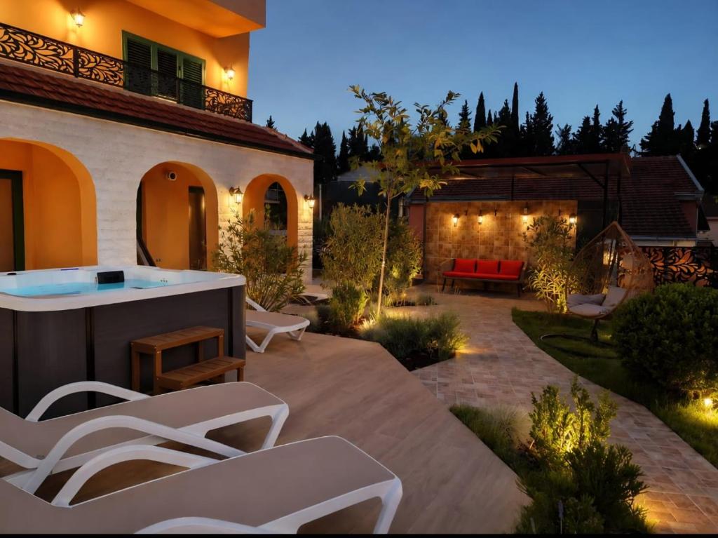 a patio with white chairs and a house at Villa AdriaBelle in Tivat