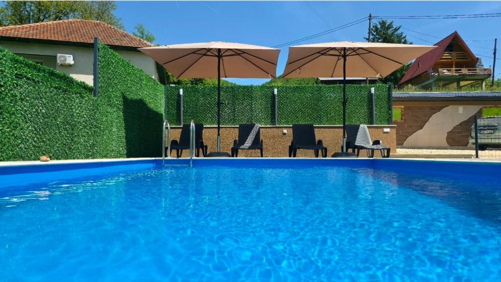 a blue swimming pool with chairs and umbrellas at Holiday Residence Šehić in Visoko